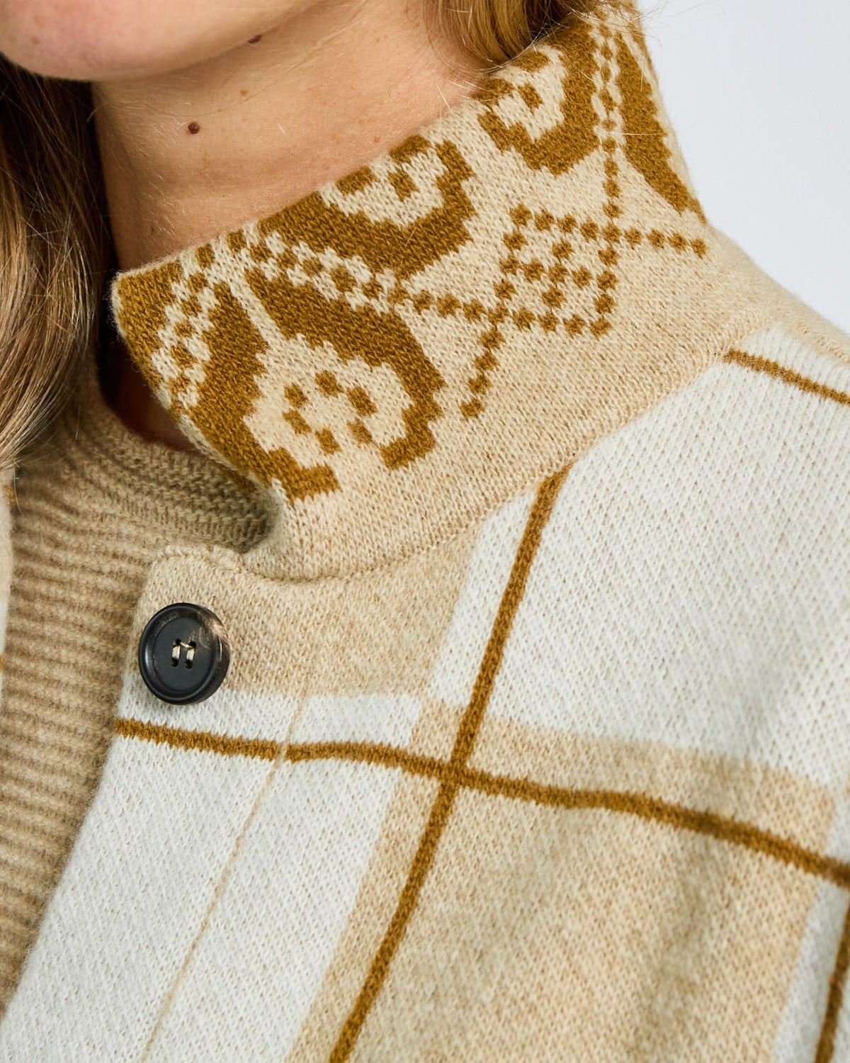 Close-up of a person wearing a patterned jacket with a button.