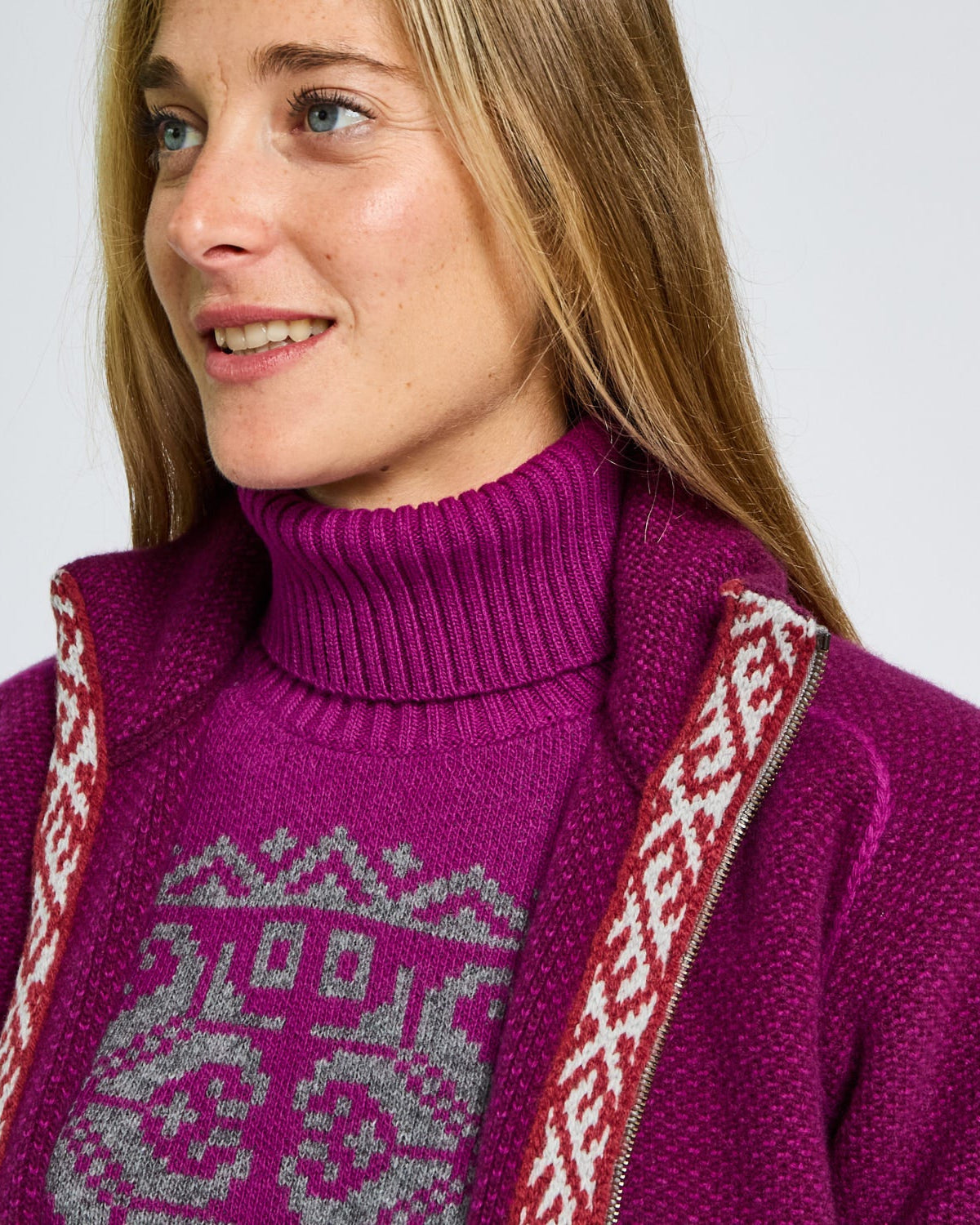 Woman wearing a purple sweater with a patterned design on a plain background