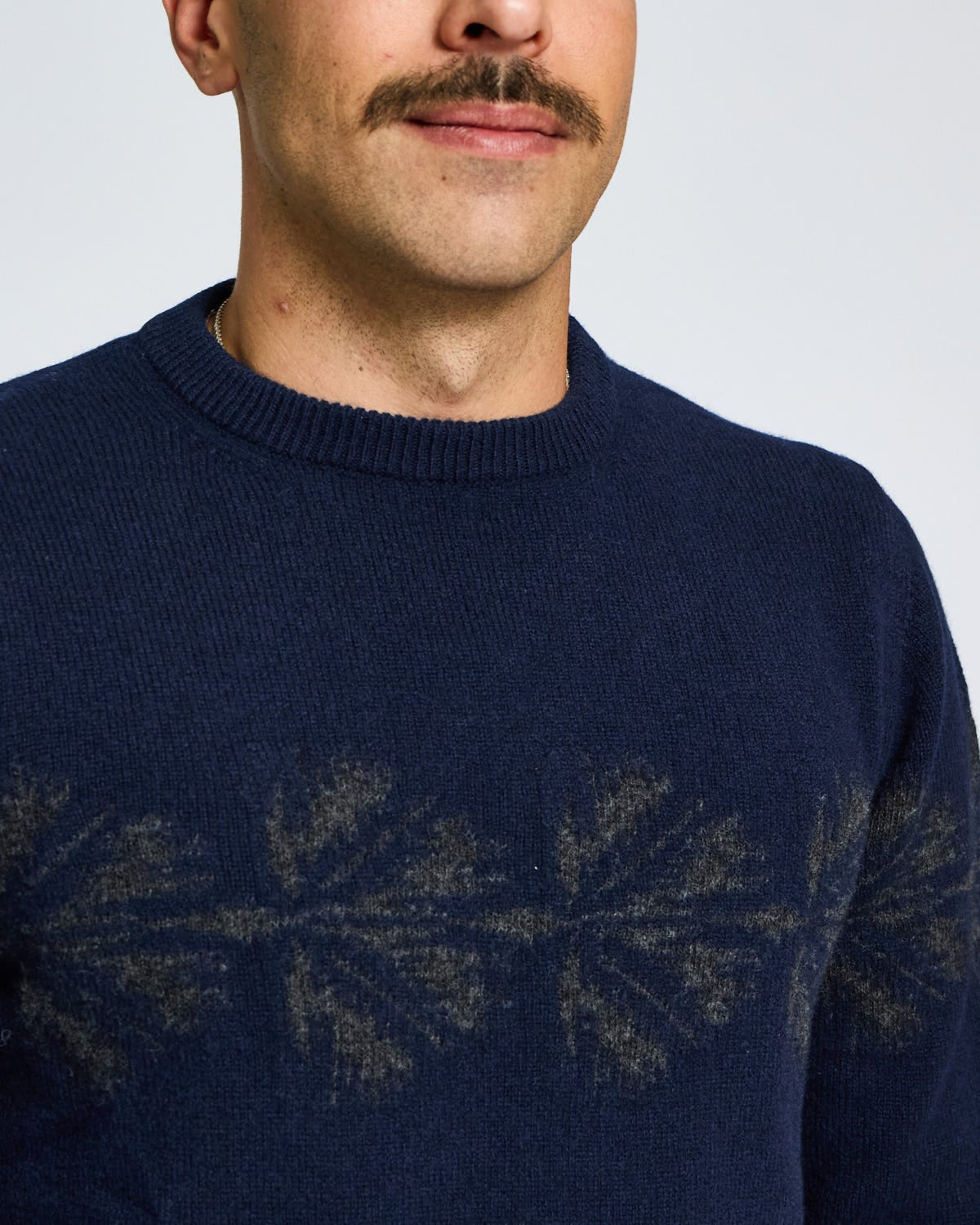 Man wearing a navy blue sweater with a subtle pattern on a plain background