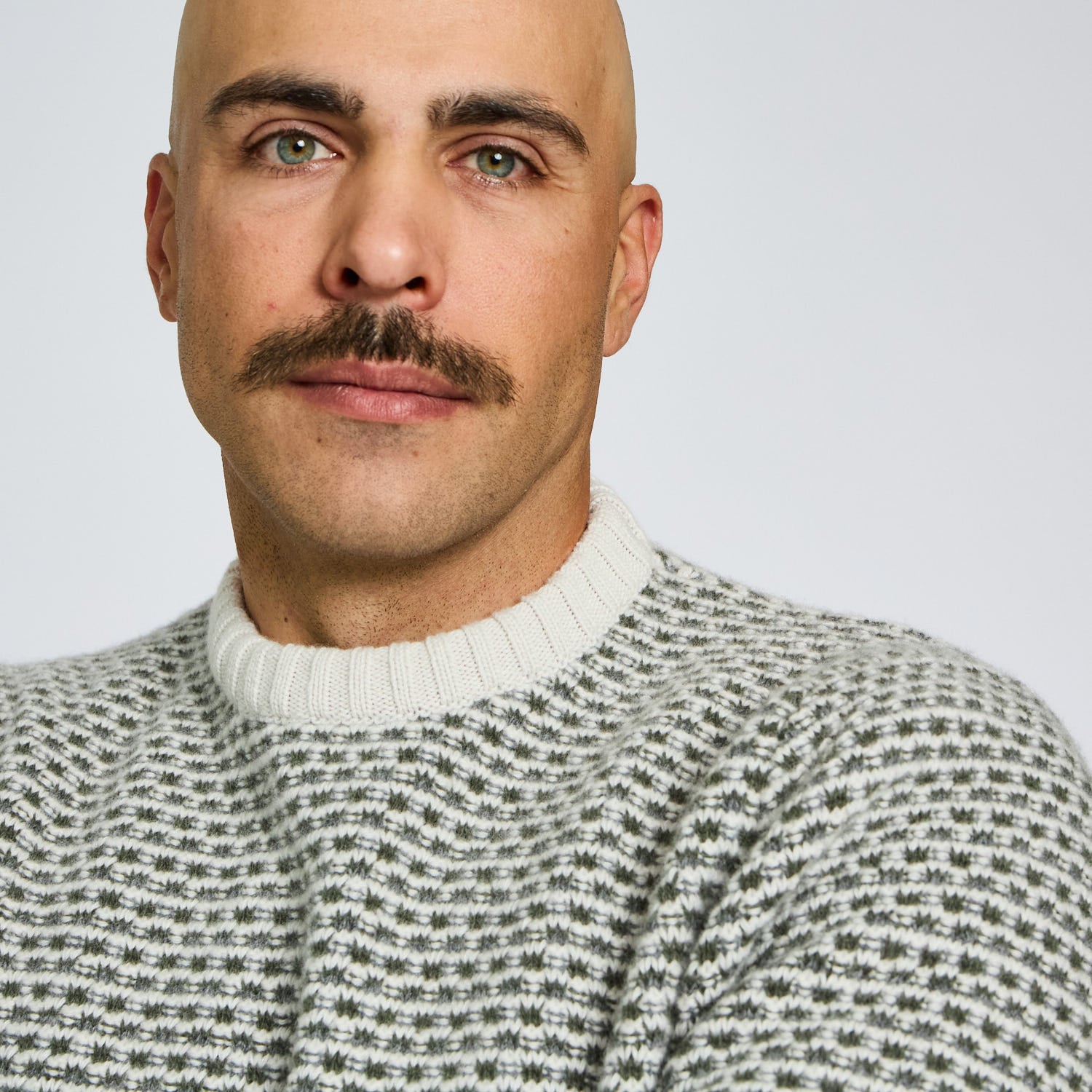 Man wearing a patterned sweater against a plain background
