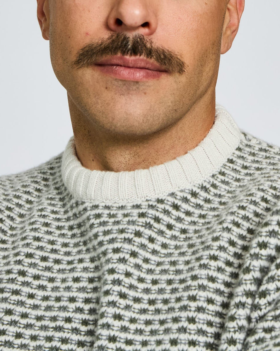 Man wearing a patterned sweater against a plain background