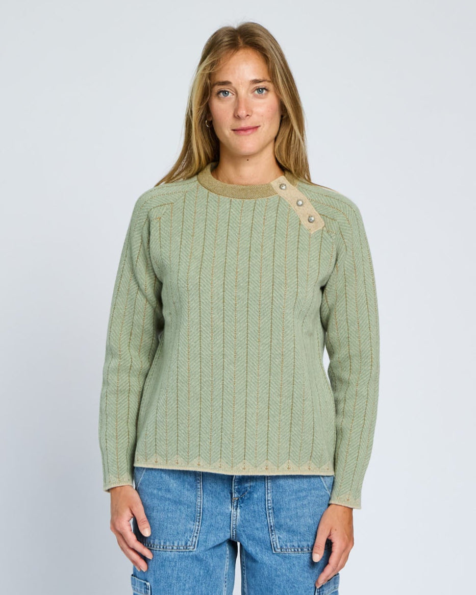 Woman wearing a green sweater with button details on a plain background