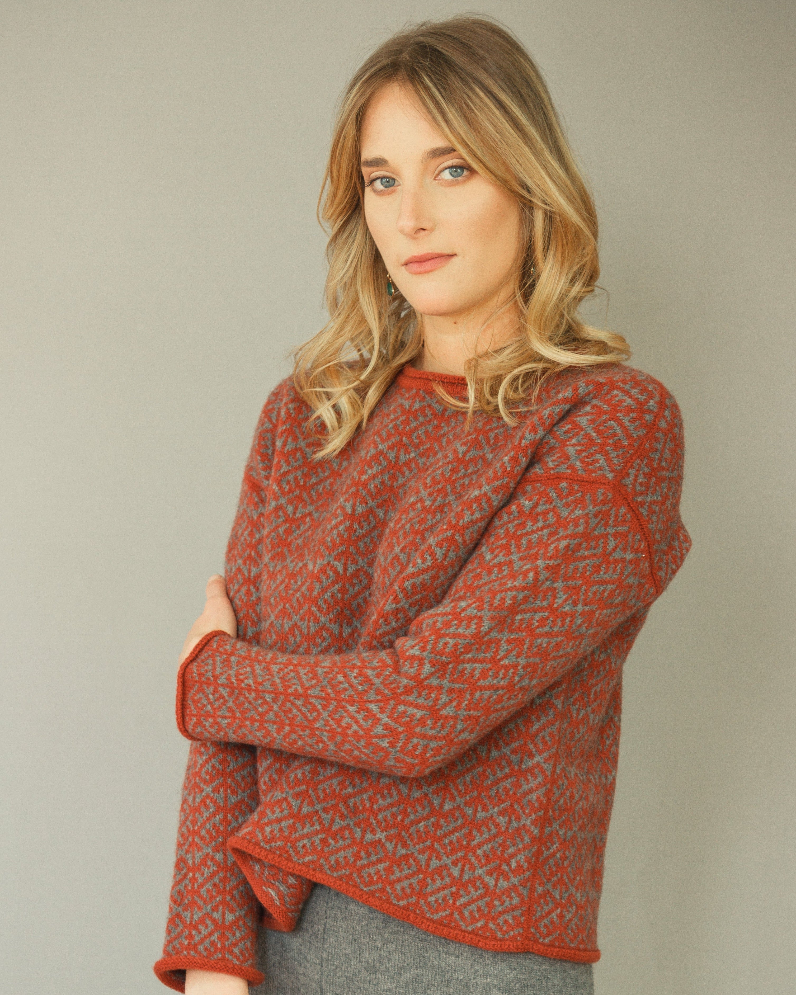 Woman wearing a patterned orange sweater against a plain background
