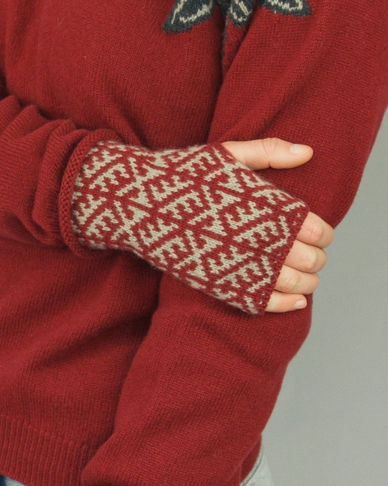 Red sweater with patterned cuffs worn by a person on a gray background