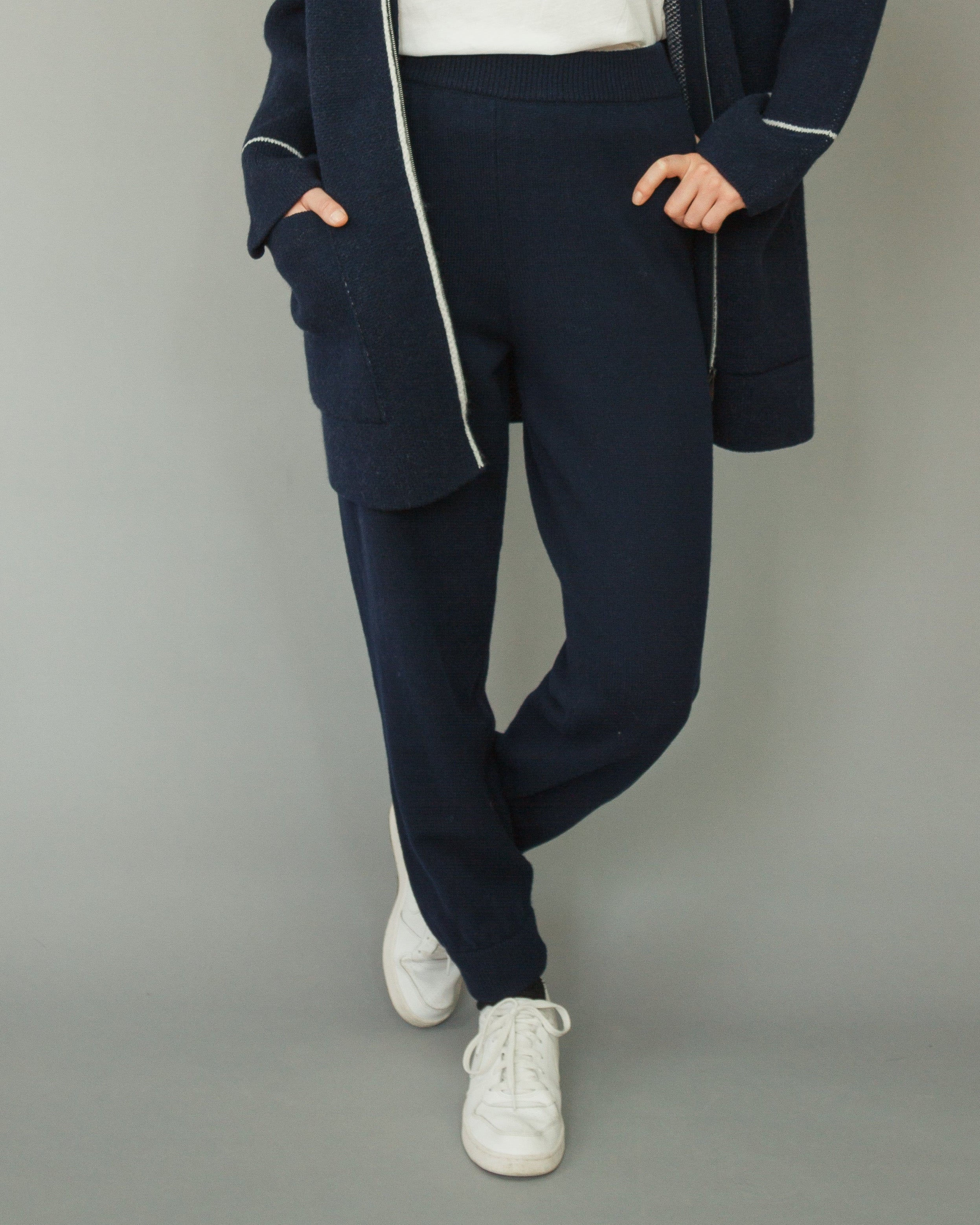 Woman wearing a navy blue coat with white floral patterns on a gray background